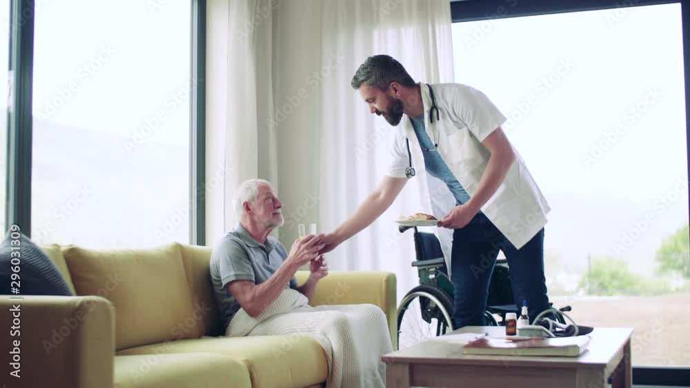Health visitor and a senior man in wheelchair during home visit. Health visitor and a senior man in wheelchair during home visit.