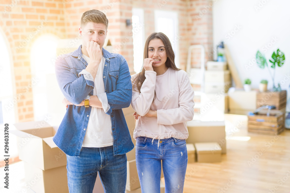 © Krakenimages.com - Beautiful young couple moving to a new house looking stressed and nervous with hands on mouth biting nails. Anxiety problem.