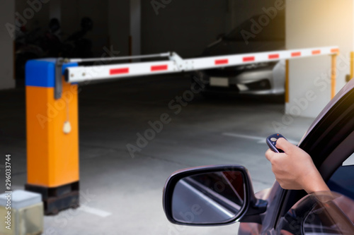 Woman in car, hand using remote control to open the automatic barrier of the car parking .Home security system and save time concept. © NIKCOA