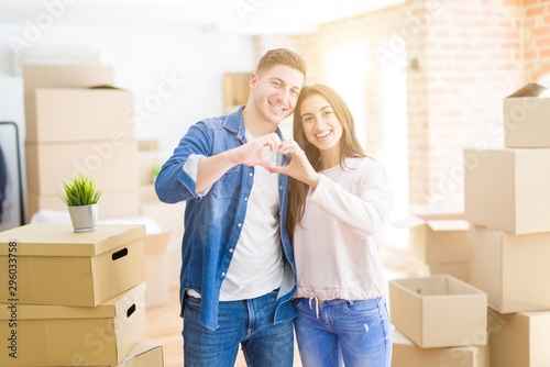 Beautiful young couple moving to a new house smiling in love showing heart symbol and shape with hands. Romantic concept. © Krakenimages.com