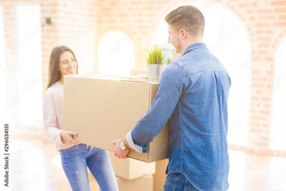 Beautiful young couple smiling in love holding a big cardboard box, happy for moving to a new home Beautiful young couple smiling in love holding a big cardboard box, happy for moving to a new home