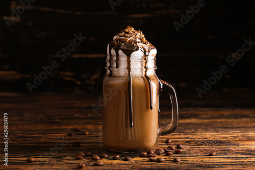 Mason jar of tasty frappe coffee on wooden table