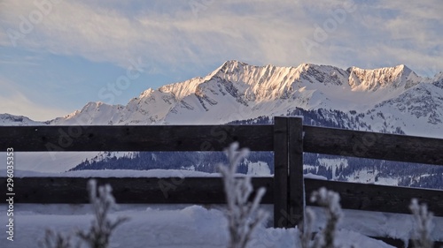 sunrise in the mountain on a cold morning with view to the alps and a wood fence in foreground
