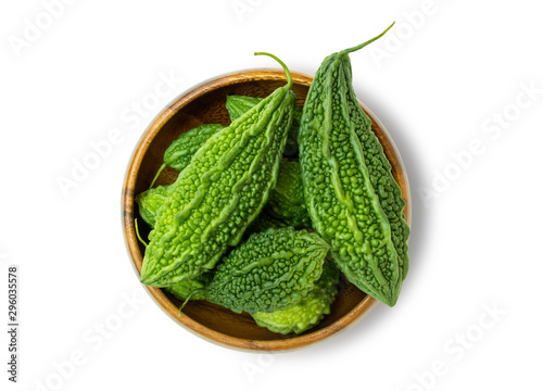 Closeup fresh bitter gourd (cucumber, Momordica Charantia) in wooden bowl isolated on white background.  Clipping path. Top view.
