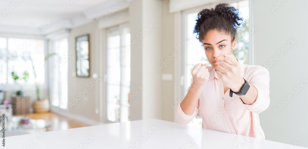 Wide angle of beautiful african american woman with afro hair Ready to fight with fist defense gesture, angry and upset face, afraid of problem