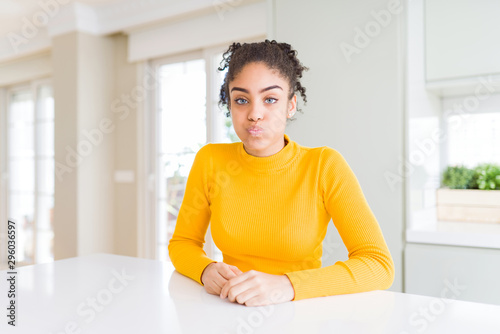 Free Download Beautiful african american woman with afro hair wearing a casual yellow sweater puffing cheeks with funny face. Mouth inflated with air, crazy expression. - GFXLoad