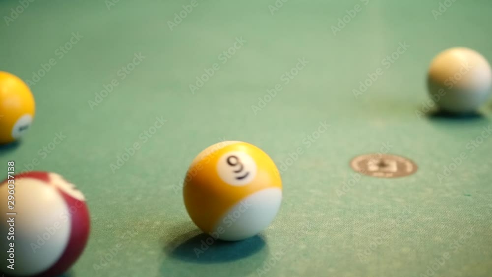 In a billiard club or a night club, billiard balls are on a pool table. Nice shot, ball nine is twisting. Concept: billiard game, pool, snooker, club, pub, entertainment, fun, interior sport In a billiard club or a night club, billiard balls are on a pool table. Nice shot, ball nine is twisting. Concept: billiard game, pool, snooker, club, pub, entertainment, fun, interior sport