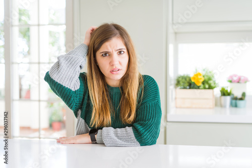 Young beautiful plus size woman wearing casual striped sweater confuse and wondering about question. Uncertain with doubt  thinking with hand on head. Pensive concept.
