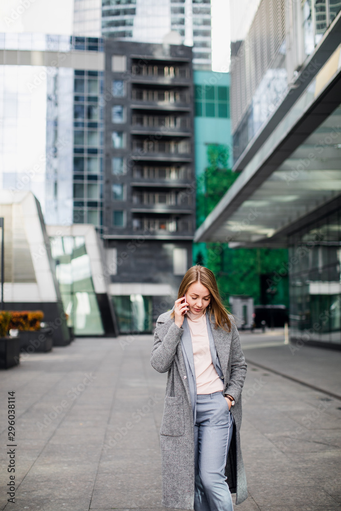 business woman talking on the phone in the background of an office building