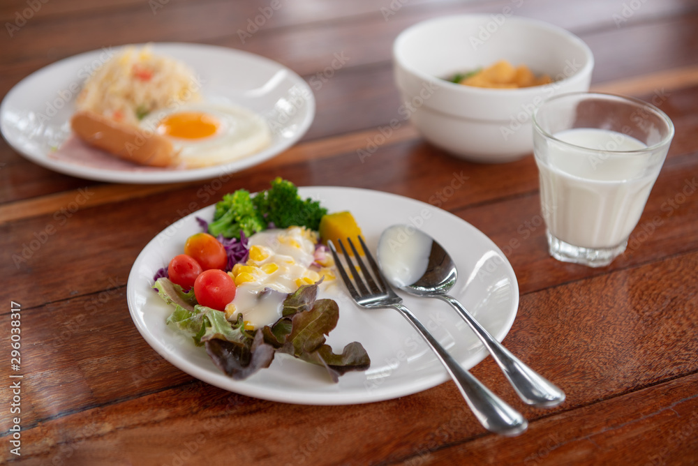 vegetable salads, sausages, fried rice, milk and orange juice on a brown wooden table vegetable salads, sausages, fried rice, milk and orange juice on a brown wooden table