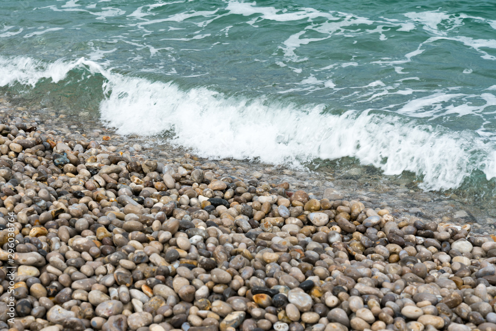 waves crash onto a rock and pebble beach waves crash onto a rock and pebble beach