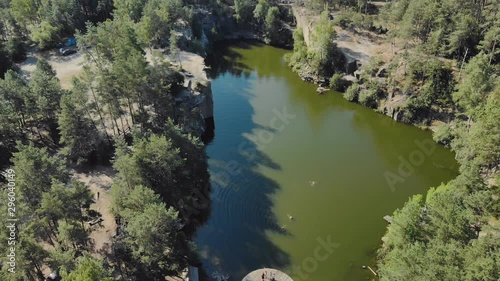 Aerial view from above of a green-tinged lake in a mountain canyon with coniferous forest, tourist camp and bathing people photo