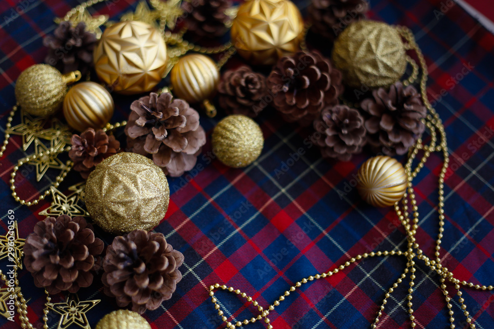 Frame of christmas decorations cones and golden balls on the blue-red plaid background. New Year Flat lays concept. Frame of christmas decorations cones and golden balls on the blue-red plaid background. New Year Flat lays concept.