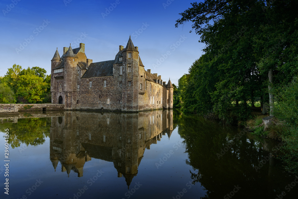 the historic Chateau Trecesson castle reflected in the pond in cool dark blue evening light