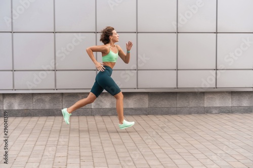 Sporty young woman athlete running on urban street in morning.