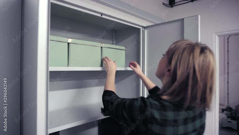 Woman checking cardboard boxes in cabinet