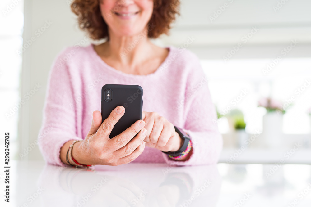 Close up of senior woman using smartphone over white table smiling confident
