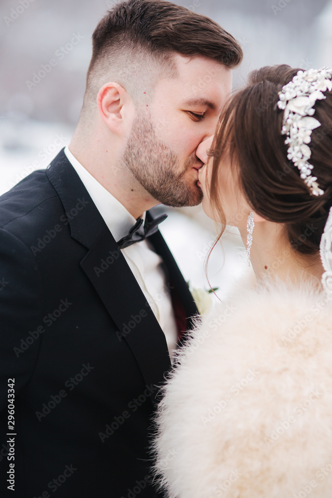 Wedding couple in winter time walking outside. Handsome bearded groom kiss beautiful bride Wedding couple in winter time walking outside. Handsome bearded groom kiss beautiful bride