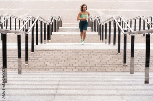 Young woman running alone up stairs outdoor.