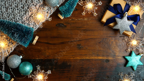 Wrapping rustic blue theme Christmas holiday gifts with kraft brown paper on vintage dark wood table, nightime overhead flat lay with copy space.