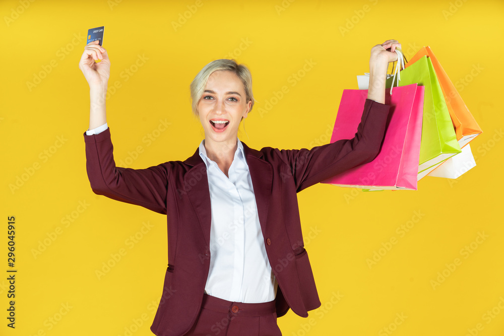 Portrait of beautiful women holding shopping bags with credit card and enjoying shopping on yellow background Portrait of beautiful women holding shopping bags with credit card and enjoying shopping on yellow background