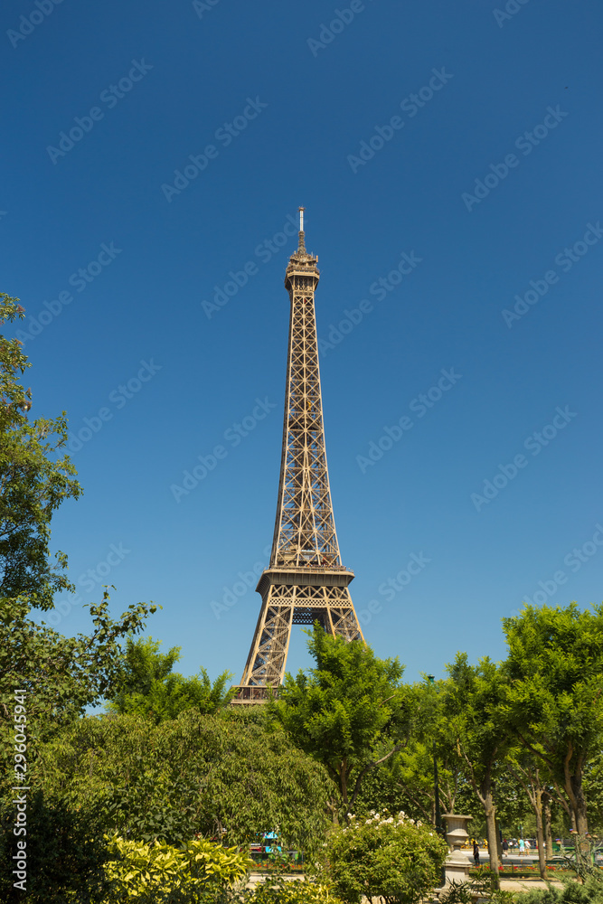 View of the Eiffel tower with the park trees in Paris, France. Famous touristic places and romantic travel destinations in Europe.	
