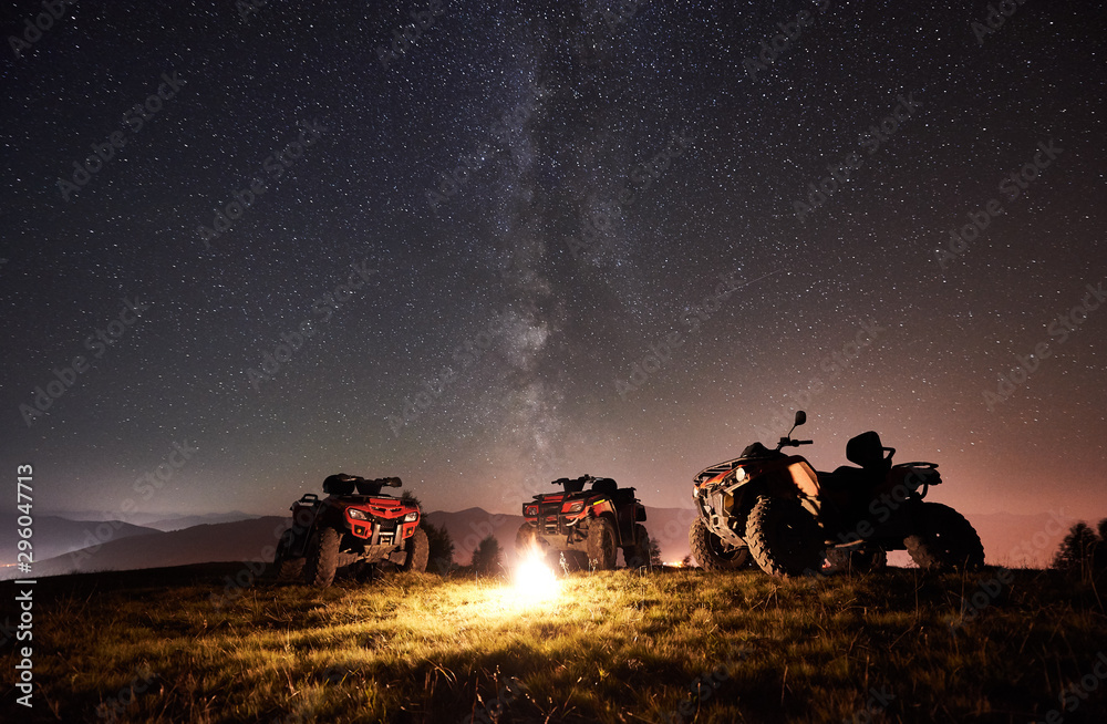 Night picture. Three atv quad motorbikes standing on the top of mountain  near burning bonpfire, under amazing night starry sky and Milky way on  background Photos | Adobe Stock