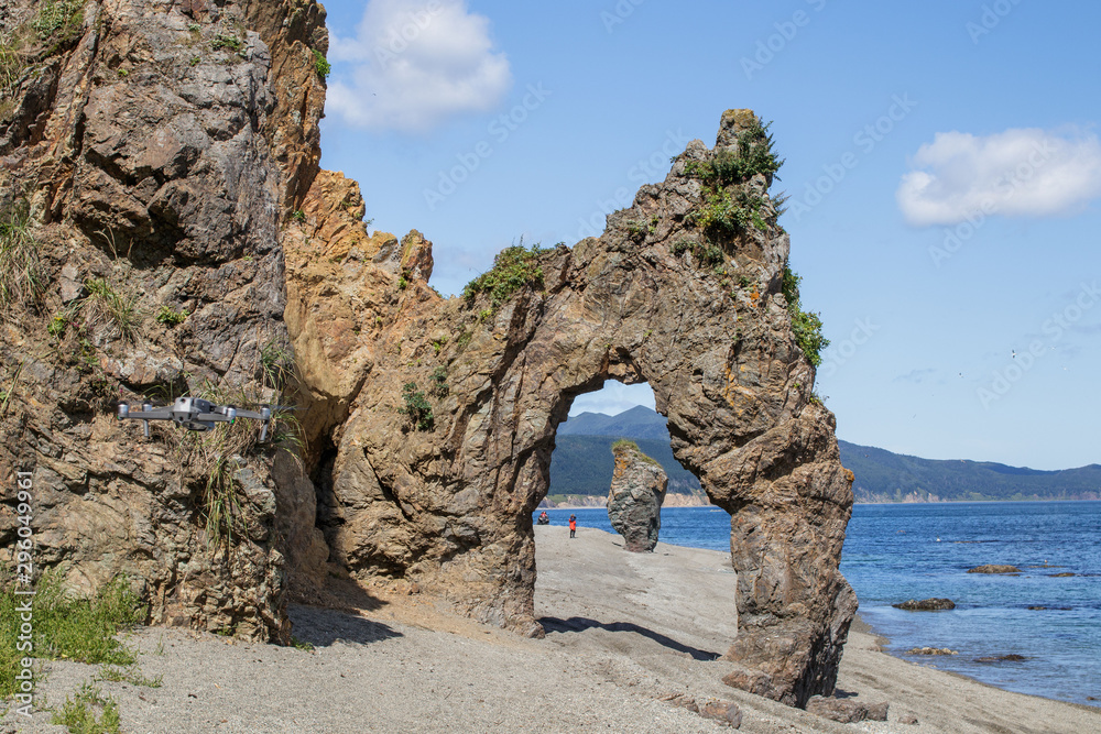 Beautiful stone natural arch, rock formation on the coast of the Sea of Okhotsk. Cape Velikan, Sakhalin Island, Russia.