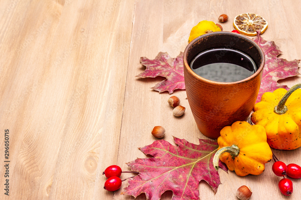 Autumn cozy mood composition. Hot tea in ceramic glass, fall leaves, pumpkins, briar, hazelnuts Autumn cozy mood composition. Hot tea in ceramic glass, fall leaves, pumpkins, briar, hazelnuts