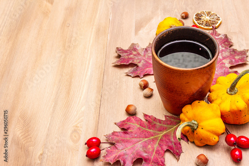 Autumn cozy mood composition. Hot tea in ceramic glass, fall leaves, pumpkins, briar, hazelnuts