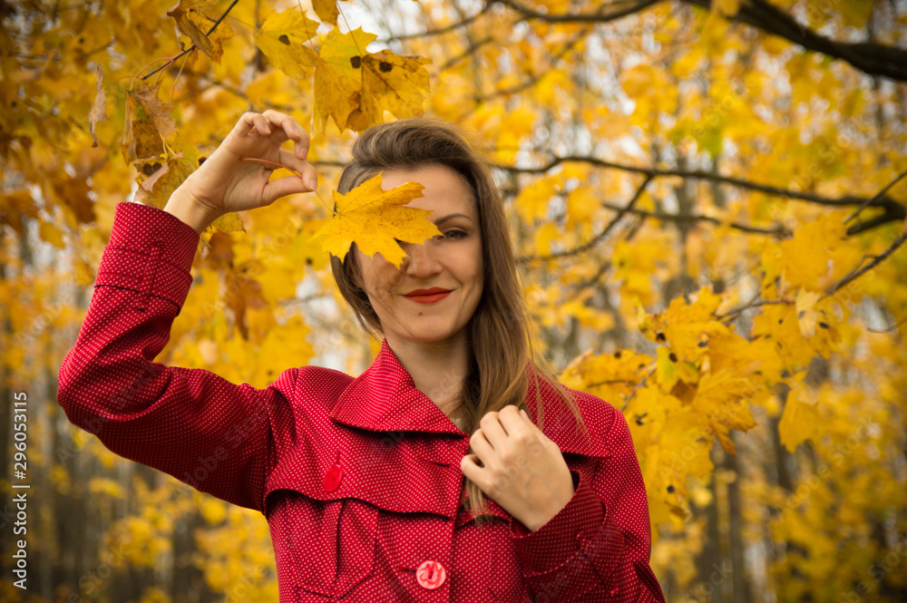 Warm autumn. Beautiful girl in a red coat holds yellow leaves in the autumn park. Warm autumn. Beautiful girl in a red coat holds yellow leaves in the autumn park.