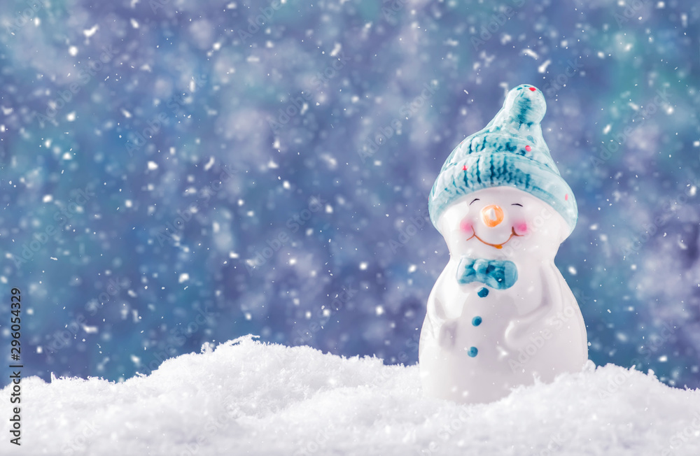 Plakat Porcelanowa figurka bałwana w zaspie, tle Bożego Narodzenia lub Nowego Roku z płatkami śniegu i światłami