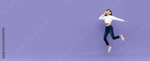 Asian woman jumping and listening to music on headphones