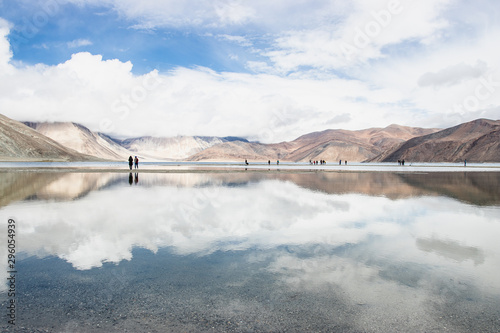 LEH LADAKH, INDIA - JUN19, 2018: Reflections of high mountain with white cloud and blue sky on the Pagong lake, Leh Ladakh, India. photo