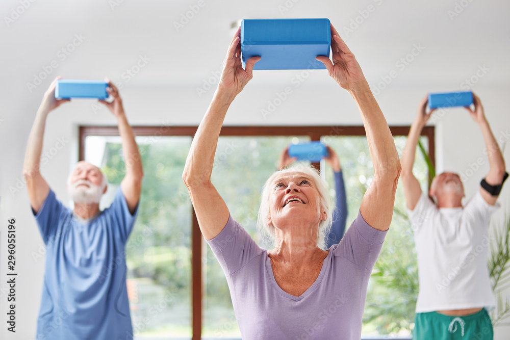 Obraz premium Seniors do back training with a yoga block