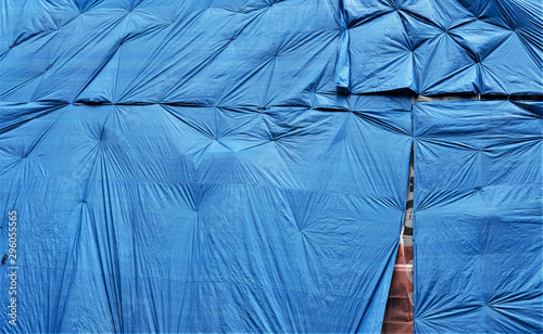 blue plastic tarpaulin protecting an old brick wall which is about to be refurbished. Abstract background