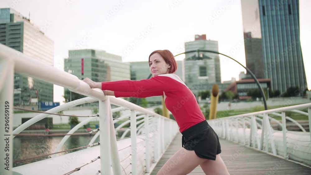 Young woman doing exercise on bridge outdoors in city, stretching. Young woman doing exercise on bridge outdoors in city, stretching.