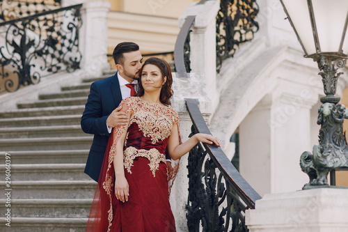 Canvas Print Beautiful woman in a long red dress walks around the city with her husband in a