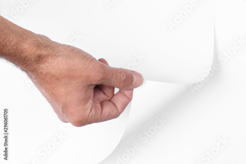 man's hand pull up  a bottom corner of a white paper sheet to uncover a neutral foreground with clipping path and copy space for your text
