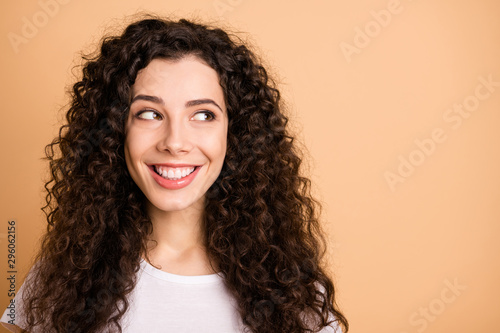 Close up photo of cheerful charming cute nice girl looking into empty space nearby smiling toothily isolated over pasel beige color background