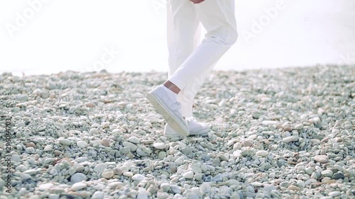 Midsection of legs of senior woman walking on rocky beach by lake. photo