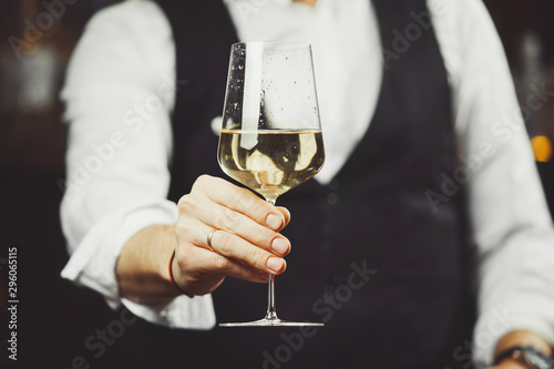 Sommelier serves a glass of white wine, close-up shot. photo