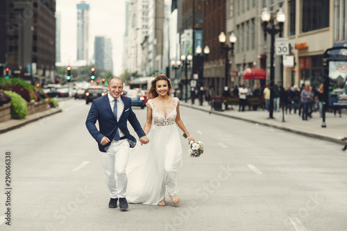 Beautiful bride in a long white dress. Handsome fiance in a blue suit. Couple in a big city