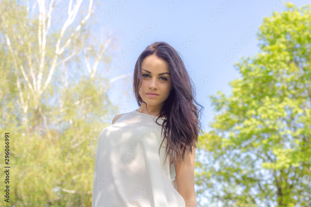 Attractive brunette woman in white dress posing in spring park Attractive brunette woman in white dress posing in spring park