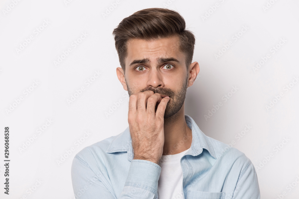 Anxious millennial man bite nails feeling terrified