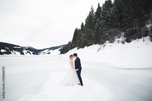Young happy couple kissing, mountains landscape in snow on the background