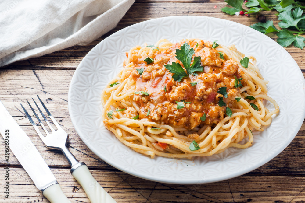 Spaghetti pasta Bolognese on white plate, wooden table
