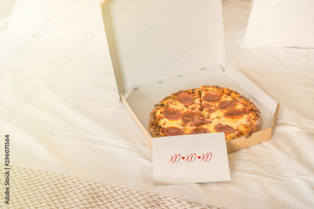 Open box of pizza on the big bed and card with Quote - xo xo xo. Valentine lettering love collection. Concept