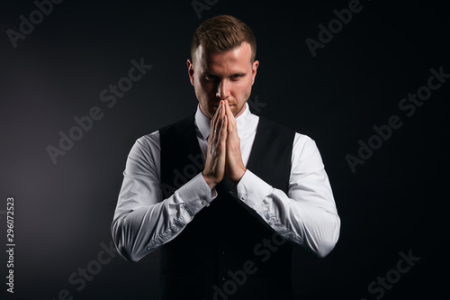 Young handsoem businessman begging and praying with hands together with hope expression, making wish to have sucessful bussiness, medittion, yoga photo