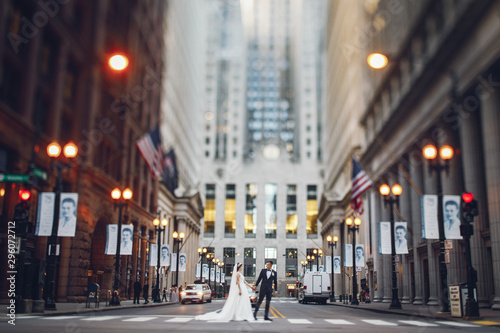 Fototapeta Naklejka Na Ścianę i Meble -  Elegant bride in a white dress and veil. Handsome groom in a blue suit. Couple in a big city